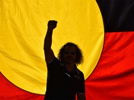 Silhouette of man standing in front of the Aboriginal flag